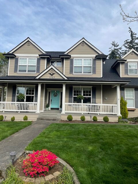 Wide view of craftsman home with complete gutter system and lush PNW landscaping