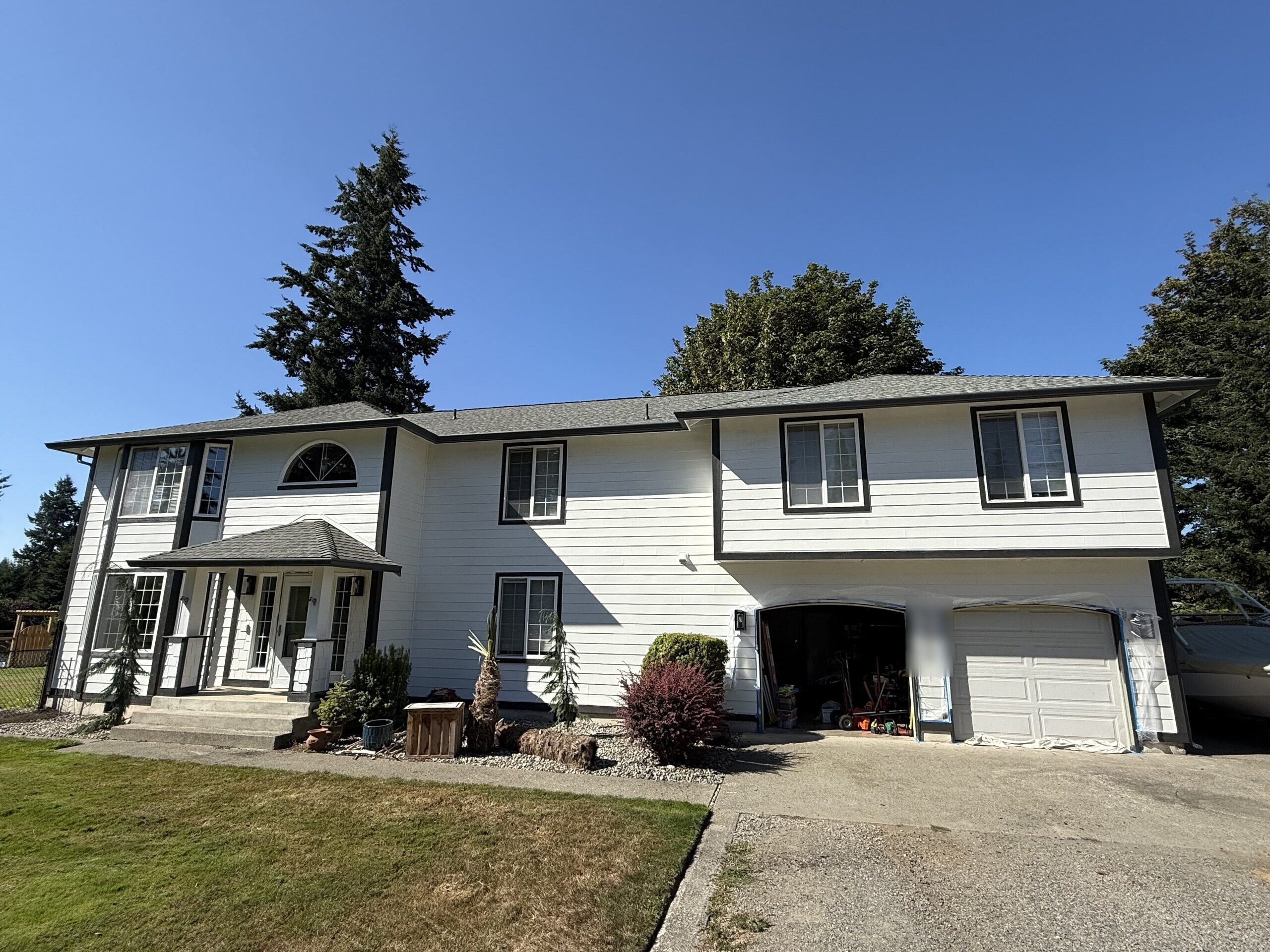 After: the same two-story home with a completed dark seamless gutter and downspout system