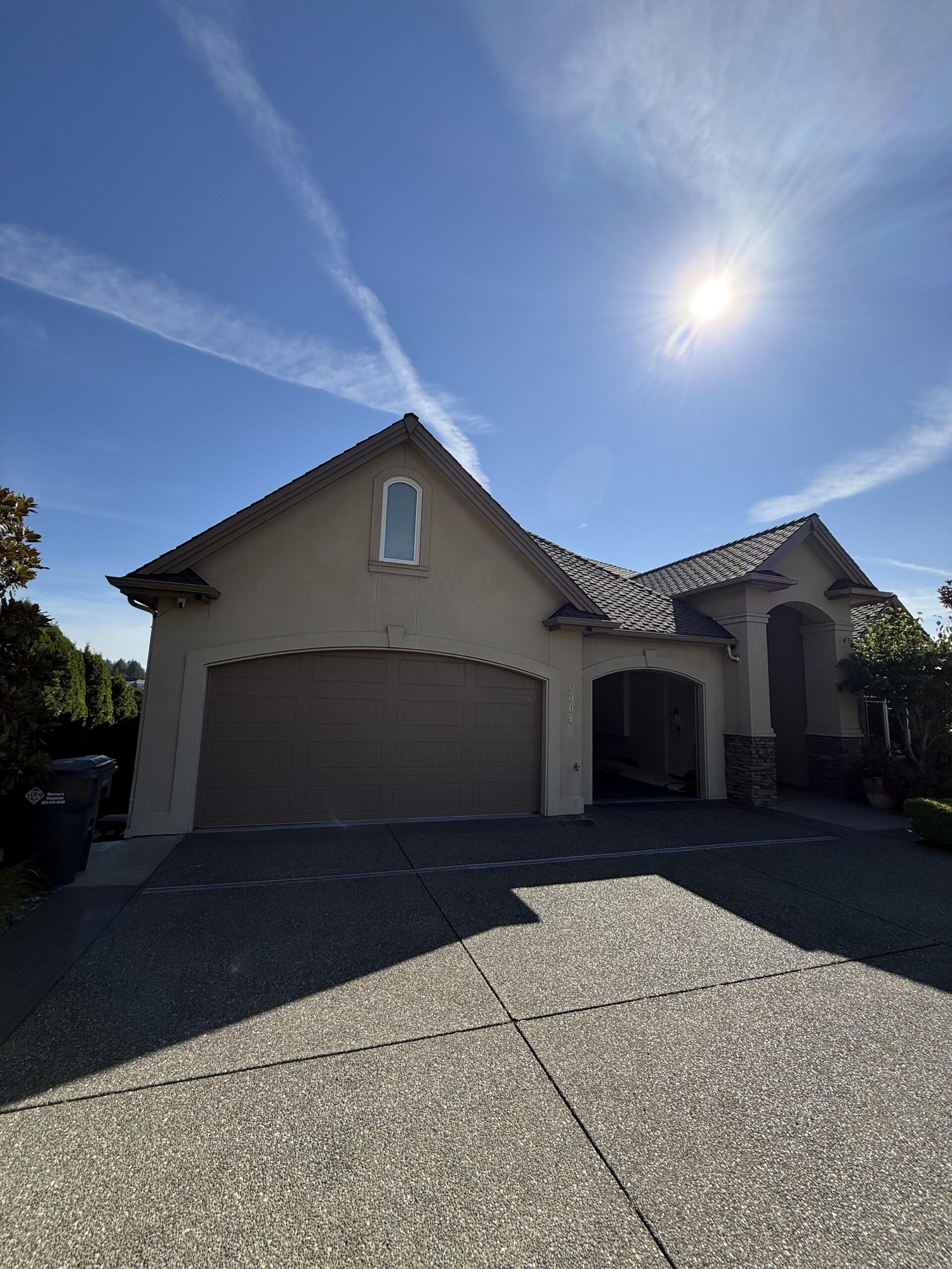 Stucco home with a tile roof and gutters along the garage and entry rooflines