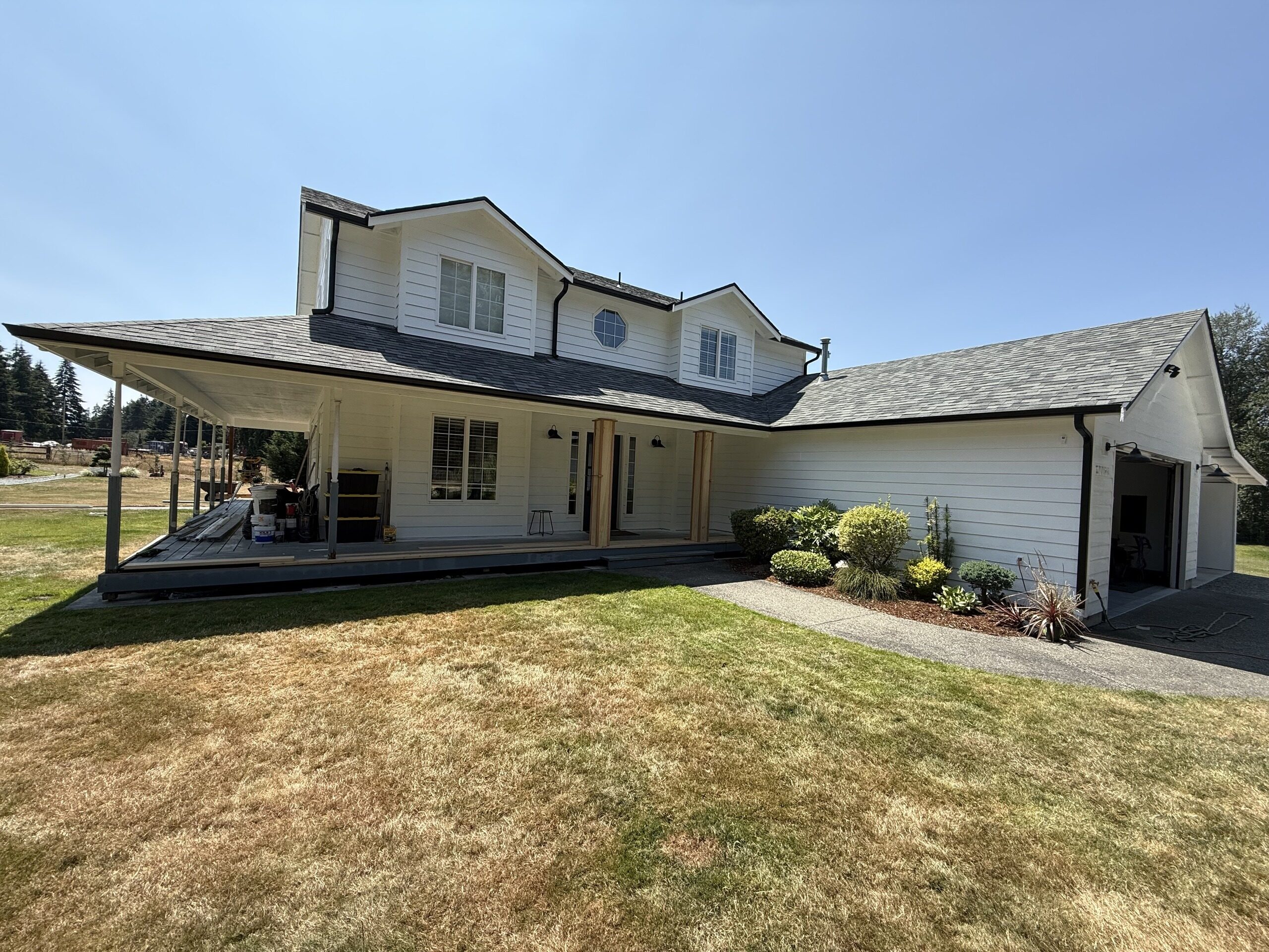 White farmhouse with a wraparound covered porch and new gutters along the full roofline