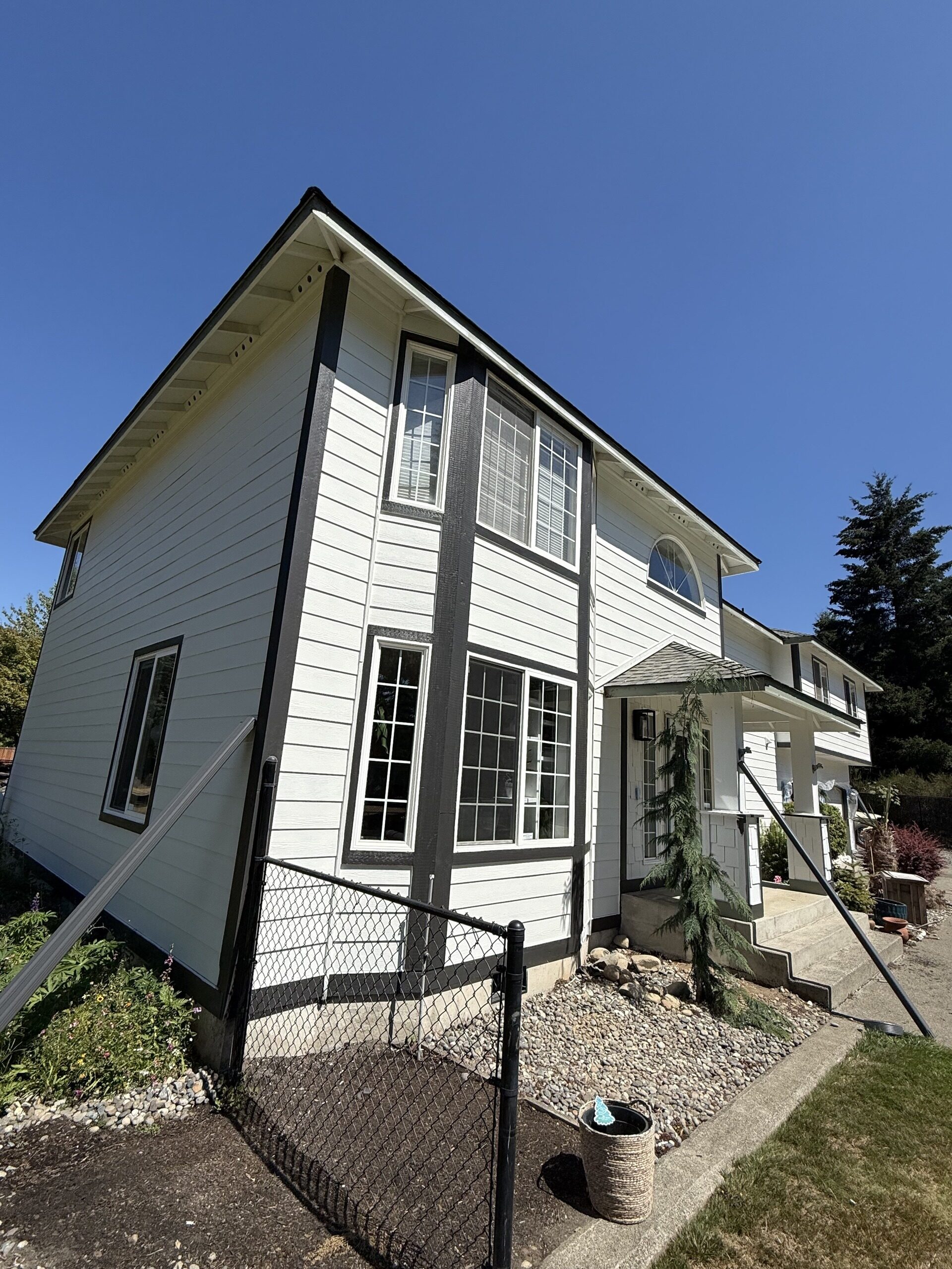 White home with dark seamless gutters and a corner downspout beside an arched entry window