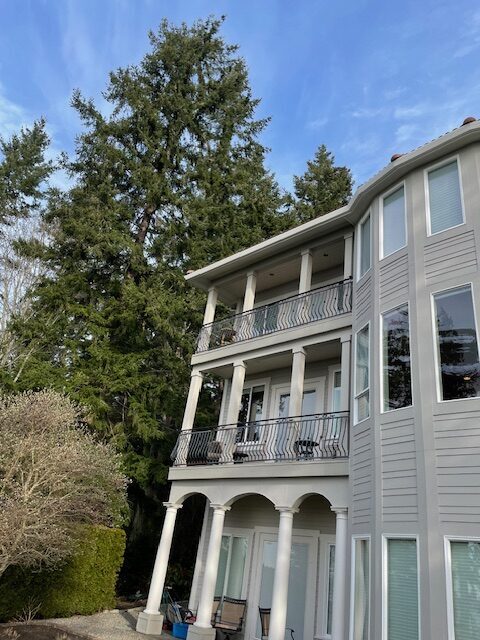 White residential home with gutter system and PNW blue sky